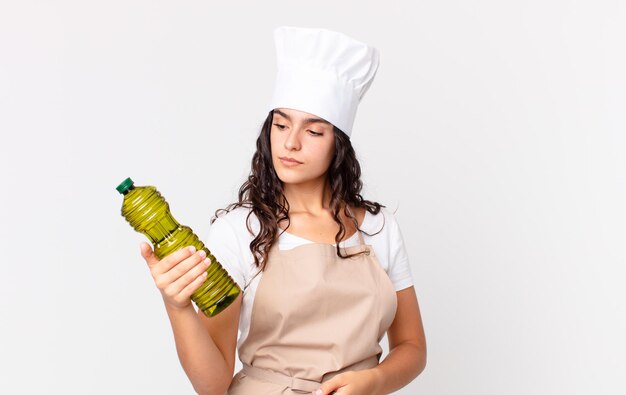 Hispanic pretty chef woman holding an olive oil bottle