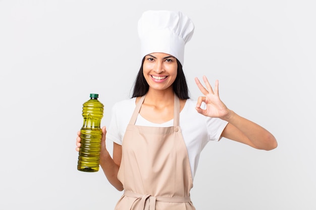 Hispanic pretty chef woman holding an olive oil bottle.