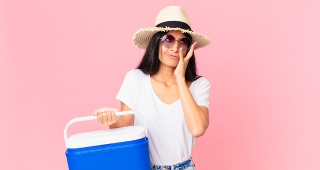 Hispanic pretty woman feeling bored, frustrated and sleepy after a tiresome with a picnic portable refrigerator