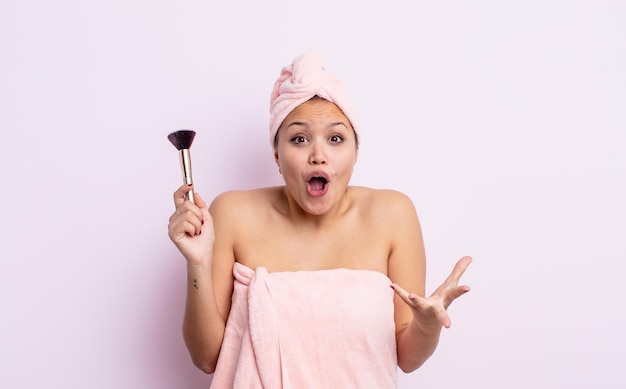 Hispanic pretty woman feeling extremely shocked and surprised. make up brush concept