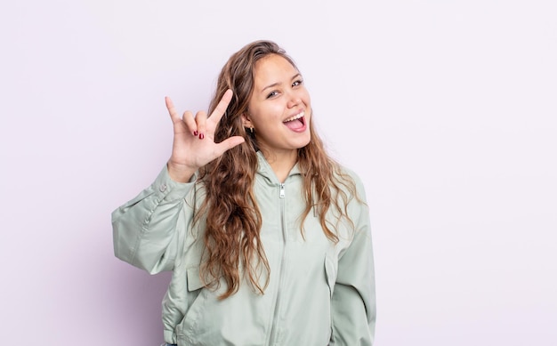 Hispanic pretty woman feeling happy fun confident positive and rebellious making rock or heavy metal sign with hand