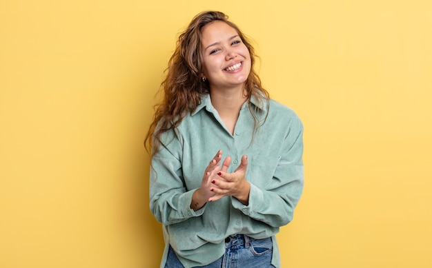 Foto bella donna ispanica che si sente felice e di successo, sorride e batte le mani, congratulandosi con un applauso