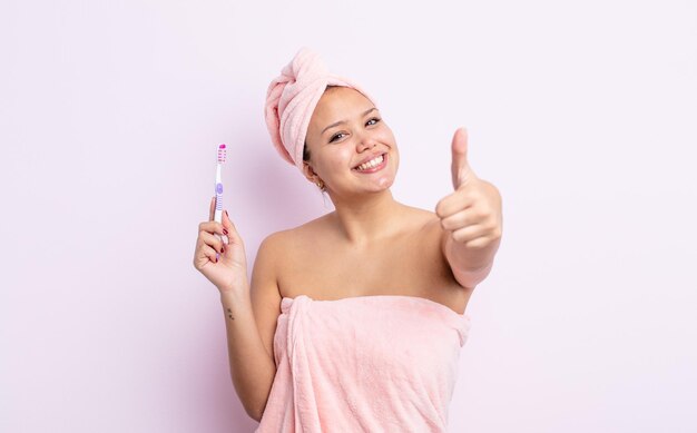 Hispanic pretty woman feeling proud,smiling positively with thumbs up tooth brush concept