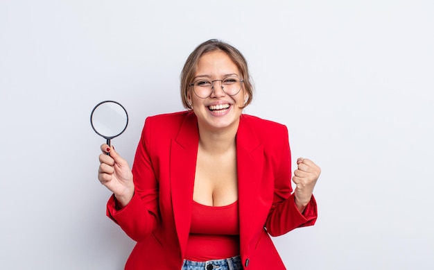 Hispanic pretty woman feeling shocked,laughing and celebrating success. magnifying glass concept