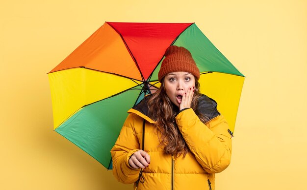 Hispanic pretty woman feeling shocked and scared umbrella concept