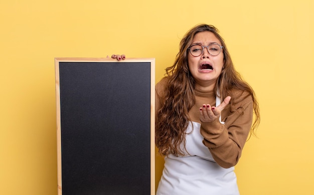 Hispanic pretty woman looking desperate, frustrated and stressed. blackboard copy space concept