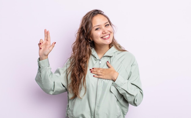 ヒスパニック系のきれいな女性は、前向きな姿勢で、幸せで、自信を持って、信頼できるように見え、笑顔で勝利のサインを示しています