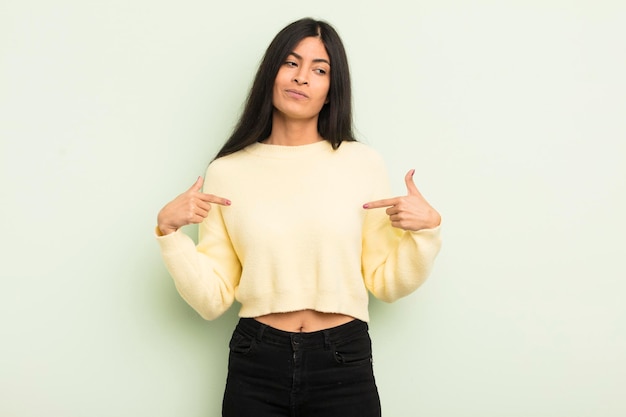 Hispanic pretty woman looking proud, positive and casual pointing to chest with both hands