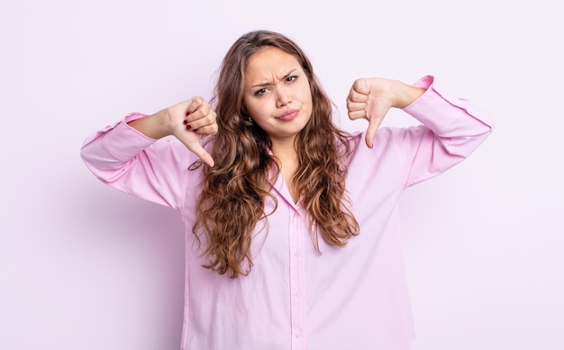 Hispanic pretty woman looking sad, disappointed or angry, showing thumbs down in disagreement, feeling frustrated