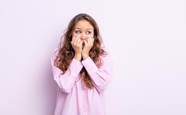 Foto bella donna ispanica che sembra preoccupata, ansiosa, stressata e impaurita, che si morde le unghie e guarda allo spazio laterale della copia