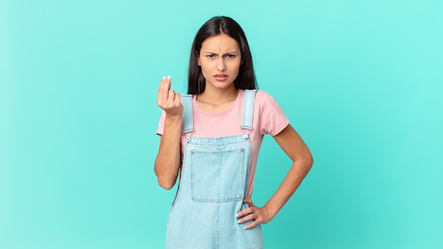 Hispanic pretty woman making capice or money gesture, telling you to pay