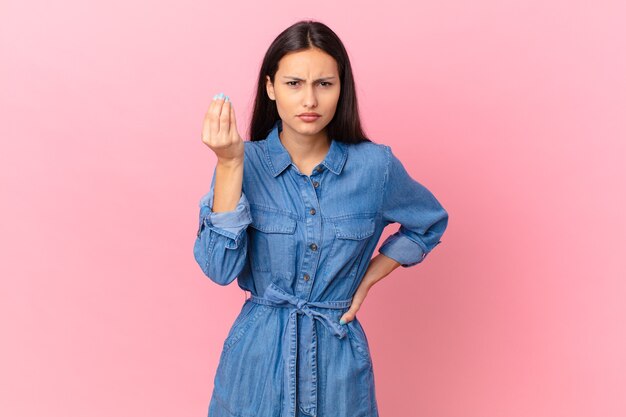 Hispanic pretty woman making capice or money gesture, telling you to pay