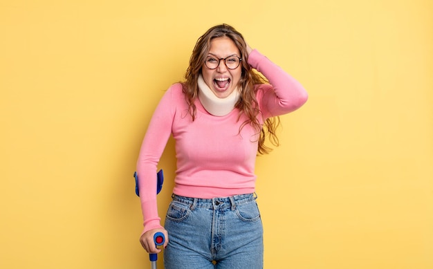 Hispanic pretty woman screaming with hands up in the air. crutch and collar accident