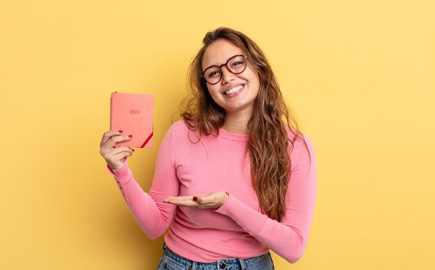 hispanic pretty woman smiling cheerfully, feeling happy and showing a concept. agenda concept