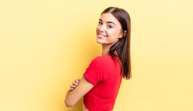 Hispanic pretty woman smiling gleefully, feeling happy, satisfied and relaxed, with crossed arms and looking to the side