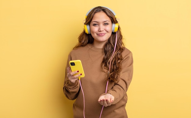 Hispanic pretty woman smiling happily with friendly and offering and showing a concept headphones and smartphone concept