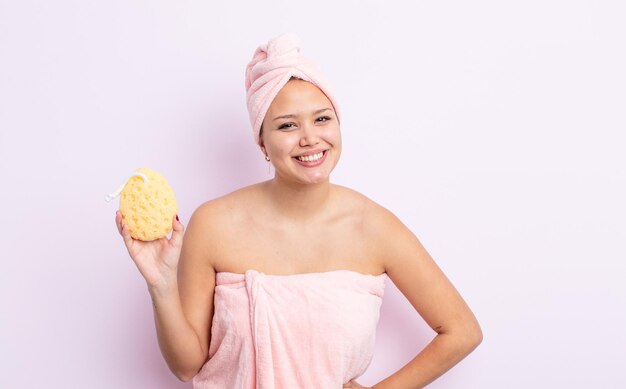 Hispanic pretty woman smiling happily with a hand on hip and confident bathrobe and sponge concept