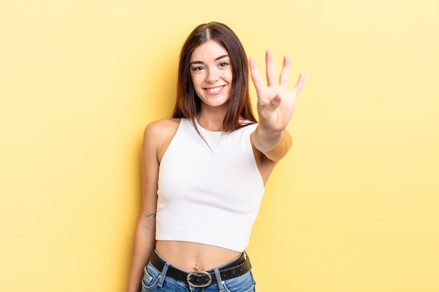 Hispanic pretty woman smiling and looking friendly, showing number four or fourth with hand forward, counting down