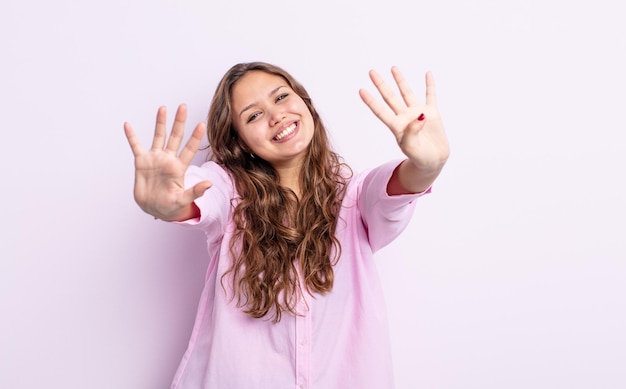 Hispanic pretty woman smiling and looking friendly, showing number nine or ninth with hand forward, counting down