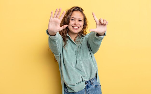 Hispanic pretty woman smiling and looking friendly, showing number seven or seventh with hand forward, counting down