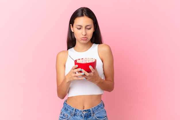 Hispanic pretty woman with a breakfast bowl with flakes