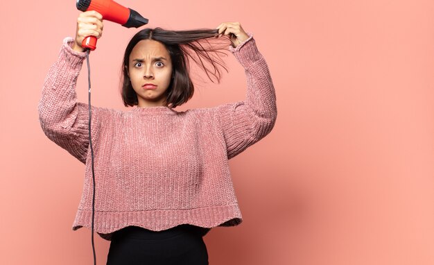 Hispanic pretty woman with a hair dryer