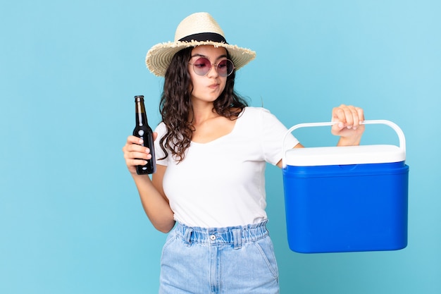 Hispanic pretty woman with a portable fridge and a beer bottle