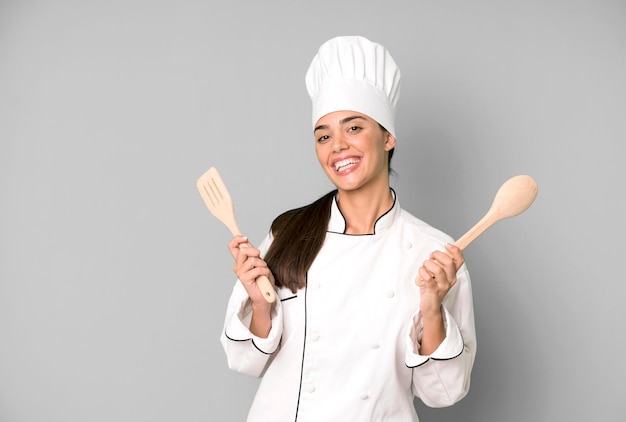 Hispanic pretty young adult and expressive chef woman with cook tools