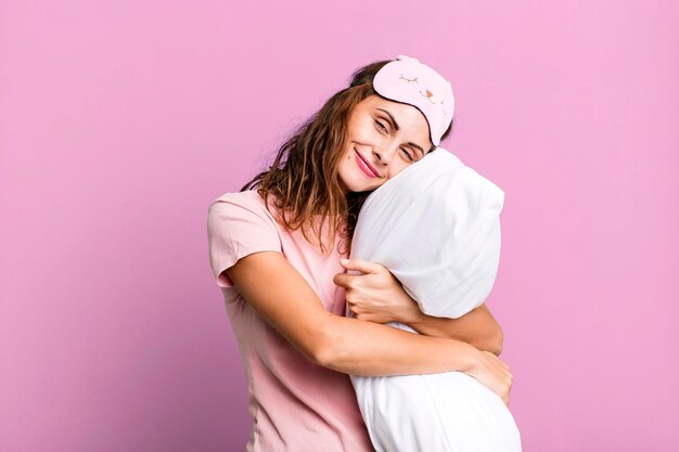 Hispanic pretty young woman wearing pajamas night wear and a pillow