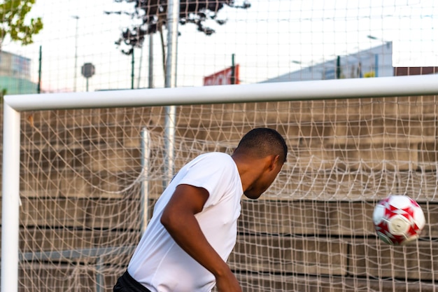 Hispanic soccer player wearing white shirt in field heading
foot ball in field