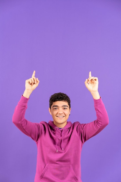 Hispanic teenager boy pointing up to copy space