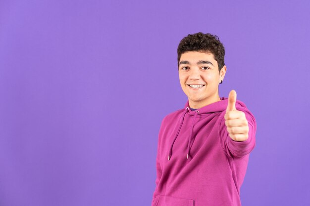 Hispanic teenager making ok sign isolated on purple background