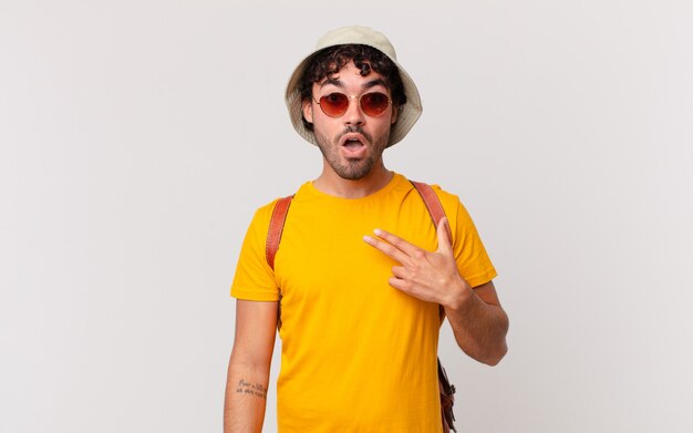 Hispanic tourist man looking shocked and surprised with mouth wide open, pointing to self