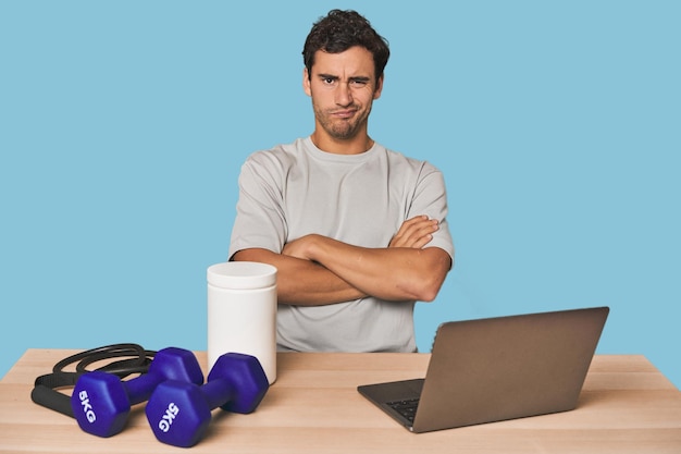 Hispanic trainer planning workout frowning face in displeasure keeps arms folded