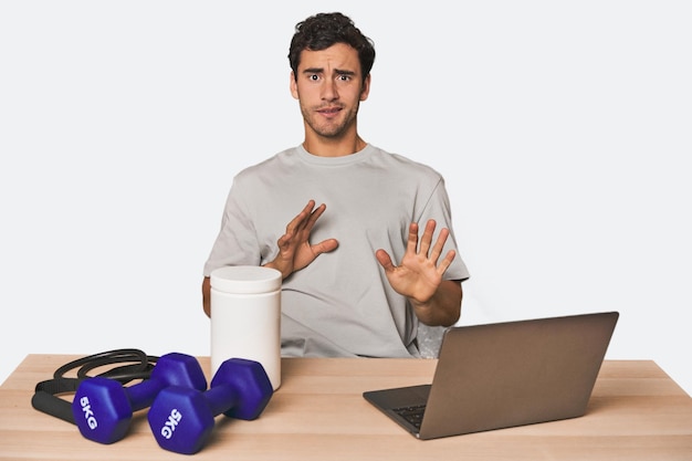 Hispanic trainer planning workout rejecting someone showing a gesture of disgust