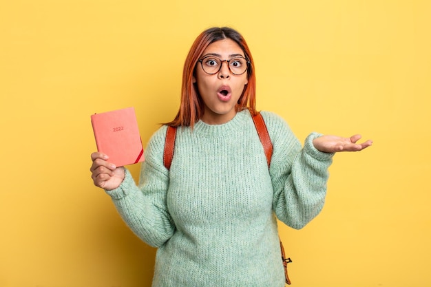 Hispanic woman amazed shocked and astonished with an unbelievable surprise student and calendar concept