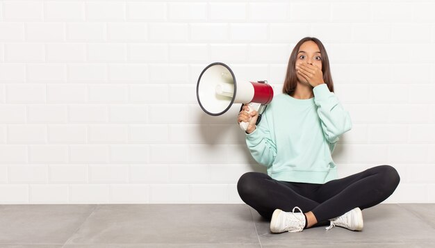 Hispanic woman covering mouth with hands with a shocked, surprised expression, keeping a secret or saying oops