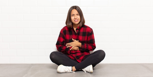 Photo hispanic woman feeling anxious, ill, sick and unhappy, suffering a painful stomach ache or flu