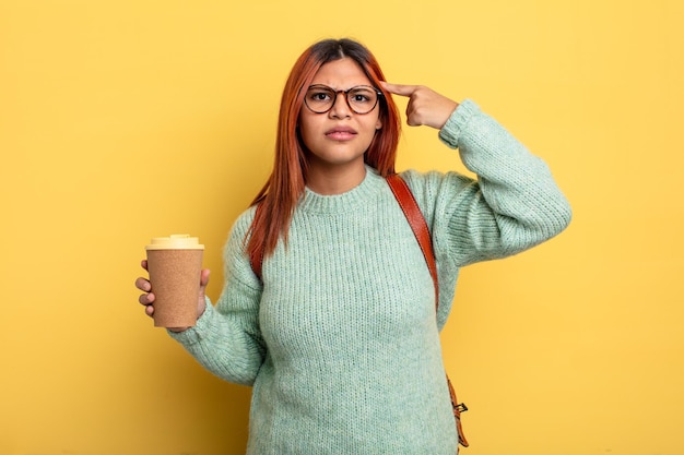Hispanic woman feeling confused and puzzled, showing you are insane. student with a coffee concept