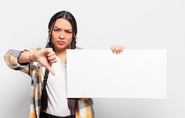 Hispanic woman feeling cross, angry, annoyed, disappointed or displeased, showing thumbs down with a serious look