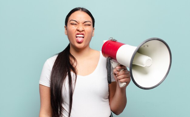 Hispanic woman feeling disgusted and irritated, sticking tongue out, disliking something nasty and yucky