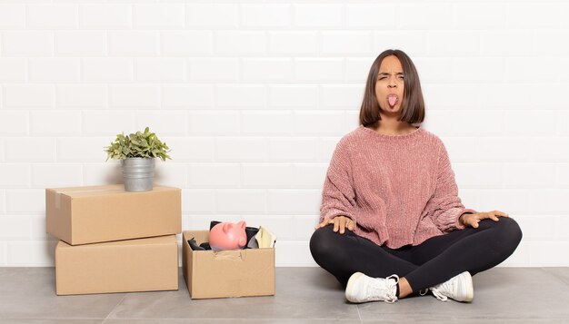 Hispanic woman feeling disgusted and irritated, sticking tongue out, disliking something nasty and yucky