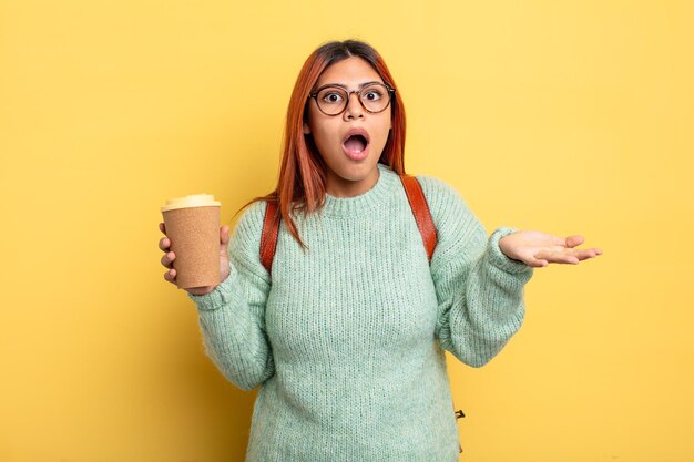 Hispanic woman feeling extremely shocked and surprised student with a coffee concept