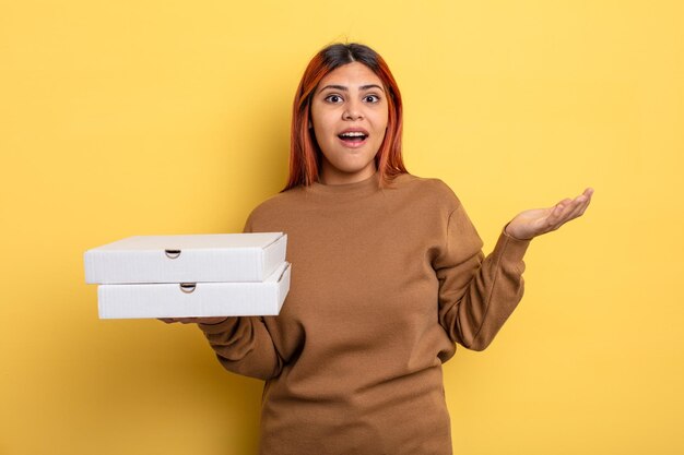 Hispanic woman feeling happy and astonished at something unbelievable. take away pizzas concept