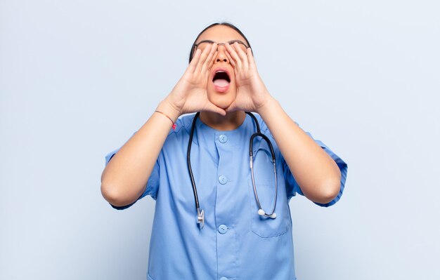 Hispanic woman feeling happy, excited and positive, giving a big shout out with hands next to mouth, calling out