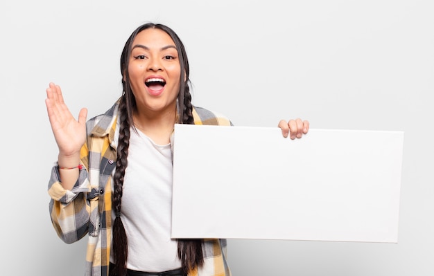 hispanic woman feeling happy, excited, surprised or shocked, smiling and astonished at something unbelievable