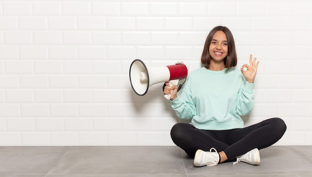 Hispanic woman feeling happy, relaxed and satisfied, showing approval with okay gesture, smiling