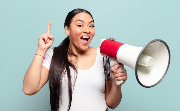 Hispanic woman feeling like a happy and excited genius after realizing an idea, cheerfully raising finger, eureka!