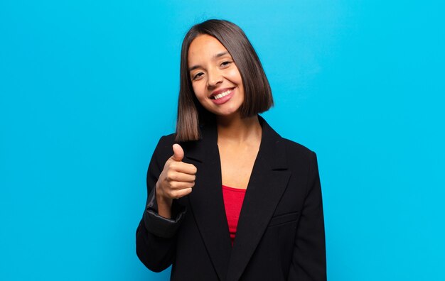 Hispanic woman feeling proud, carefree, confident and happy, smiling positively with thumbs up