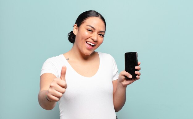 Hispanic woman feeling proud, carefree, confident and happy, smiling positively with thumbs up